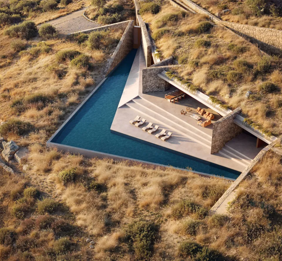 Aerial rendering of a triangular pool and stepped terrace framed by stone walls and planted roofs on a golden hillside