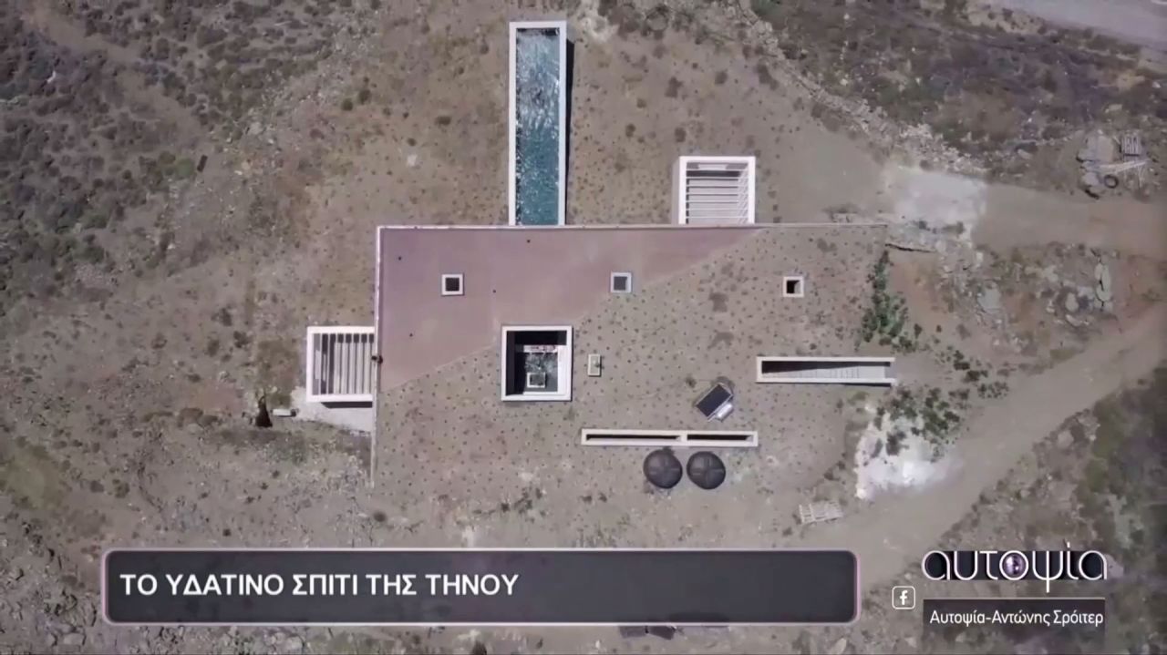 Aerial TV still looking straight down on a flat-roofed house with a long pool, captioned in Greek for the Alpha TV show Aftopsia