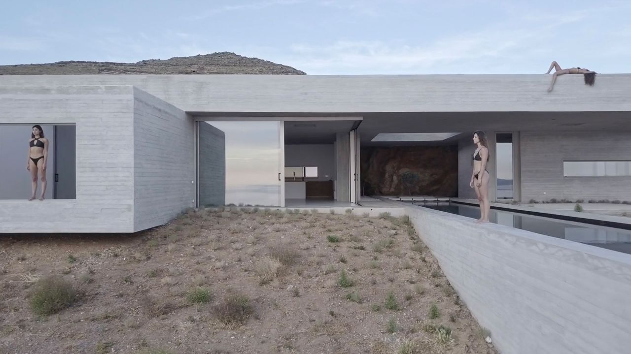 Board-marked concrete house with a long pool edge and open sliding glass, three people standing and lying on the walls and roof
