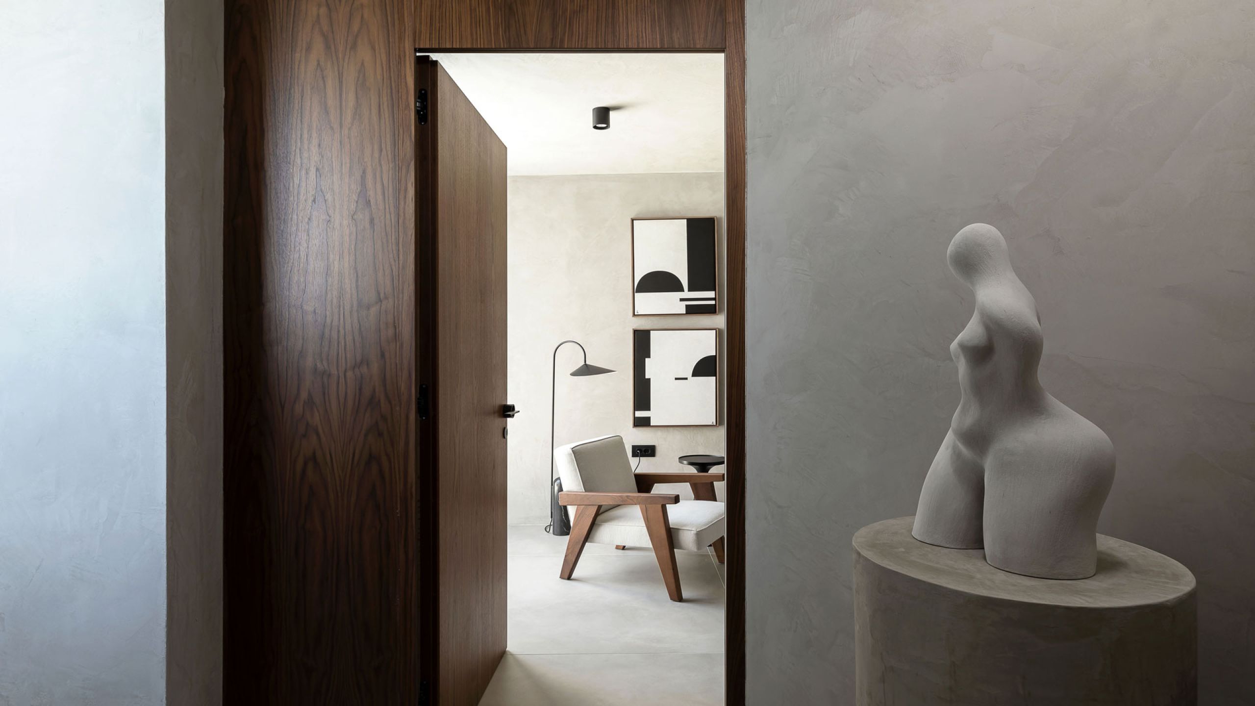 Pnoes Tinos bedroom with a long window onto the pool and sea, floating timber desk, shelving niches and a framed arch print
